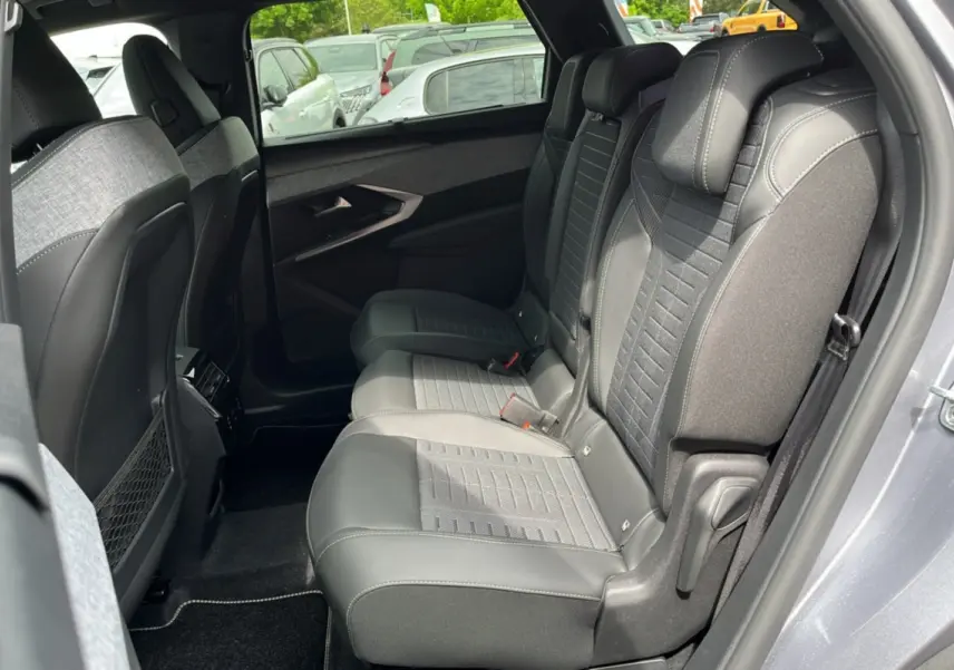 Vue intérieure côté droit des sièges arrière en tissu et cuir gris du Peugeot 3008 Hybrid 145 2025 avec porte ouverte.