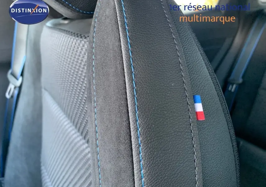 Gros plan sur le siège avant en cuir noir avec surpiqûres bleues et drapeau tricolore français du Renault Austral 2024.