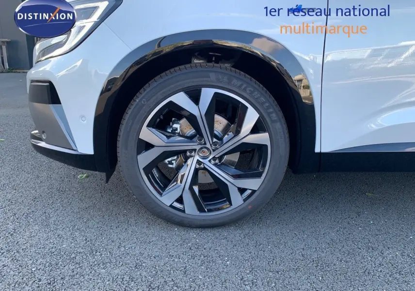 Gros plan sur la roue avant gauche du Renault Austral blanc métal avec jante alliage bicolore et toit noir visible.