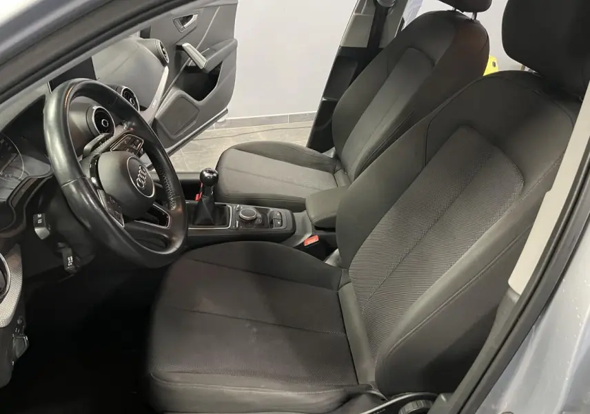 Intérieur avant droit de l'Audi Q2 gris 2019 avec sièges en tissu noir et volant multifonction en cuir.