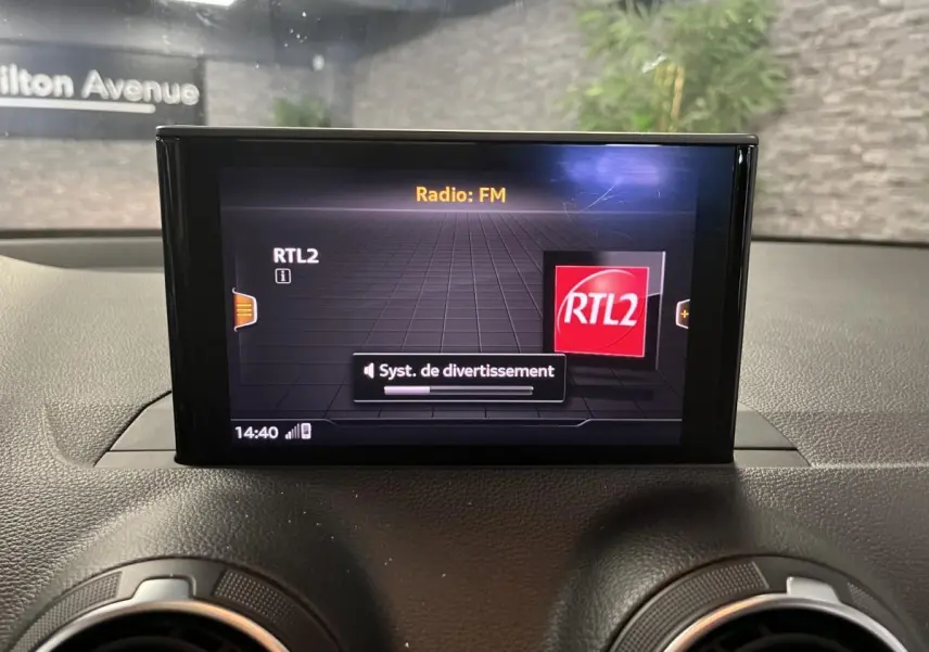 Écran central multimédia affichant la radio FM RTL2 sur le tableau de bord de l'Audi Q2 gris.