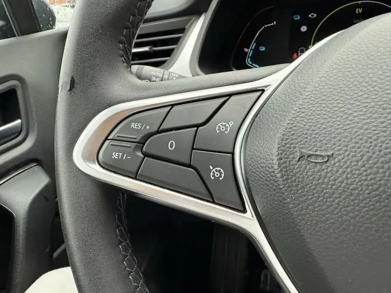 Gros plan sur les commandes de régulateur de vitesse au volant d'un Renault Captur E-Tech 145 Zen 2022, intérieur noir.
