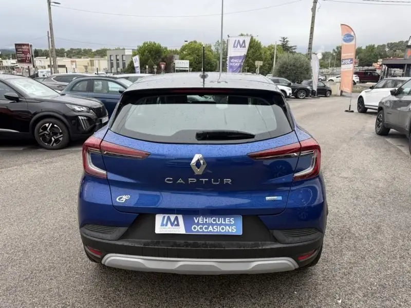 Vue arrière d'un Renault Captur E-Tech 145 Zen bleu métal 2022 avec logo hybride et plaque "Véhicules Occasions" visible.