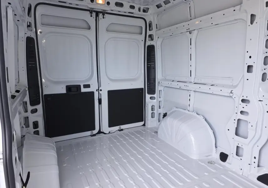 Intérieur du fourgon FIAT Ducato blanc vu de l'arrière, montrant la zone de chargement tôlée et spacieuse.