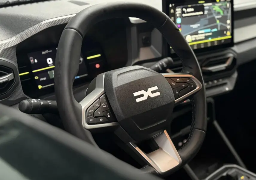 Vue rapprochée du volant multifonction et du tableau de bord digital du Dacia Duster 2026, intérieur moderne.