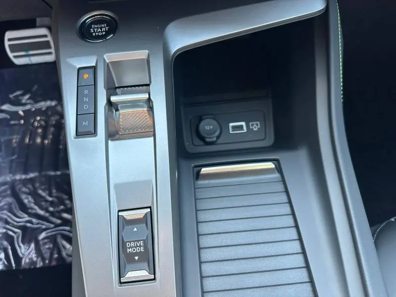 Vue rapprochée de la console centrale grise avec sélecteur de boîte auto et bouton Drive Mode de la Peugeot 308 rouge.