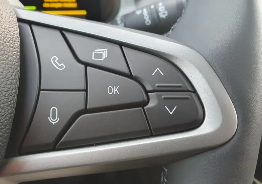 Gros plan sur les commandes multifonctions au volant du Dacia Bigster 2026, boutons noirs avec contour argenté.