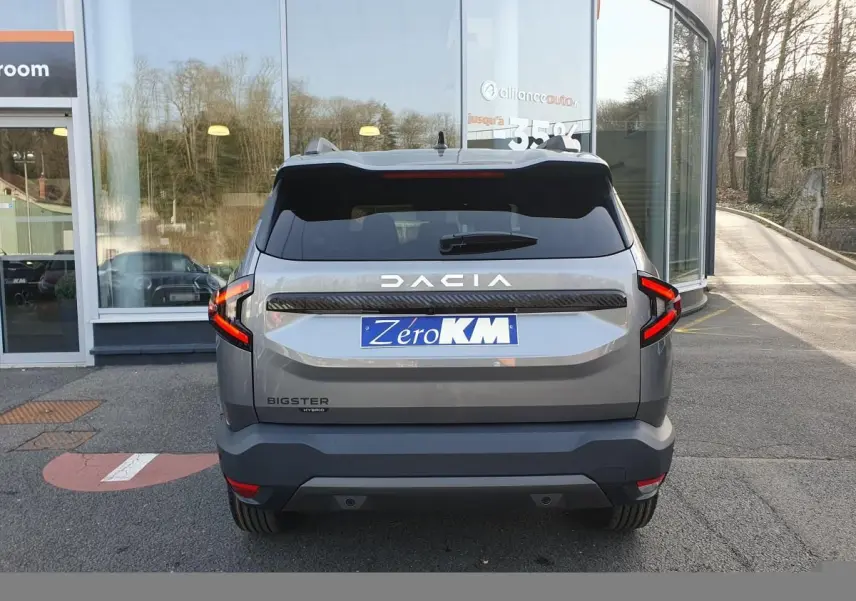 Vue arrière d’un Dacia Bigster gris schiste avec feux LED en forme de C et logo DACIA lumineux.