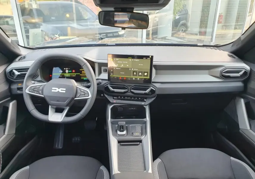 Vue intérieure avant du tableau de bord du Dacia Bigster gris schiste avec écran tactile central et volant multifonction.