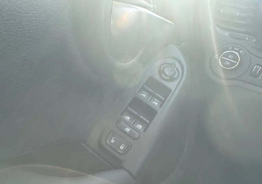 Vue rapprochée du panneau de commandes des vitres électriques et rétroviseurs du côté gauche d’un Fiat 500X bleu MY23.