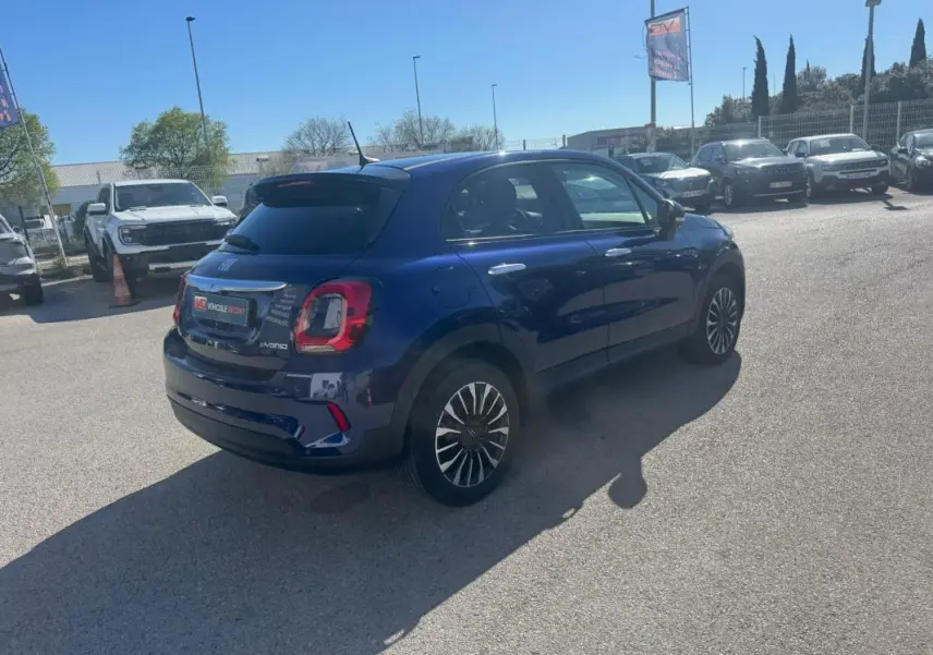 Vue 3/4 arrière droite d'une FIAT 500X bleu avec jantes classiques et feux arrière distinctifs, stationnée en extérieur.
