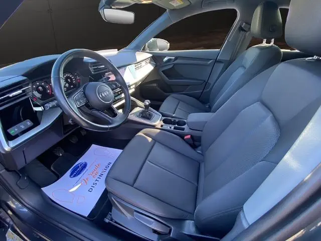 Intérieur avant droit de l'Audi A3 Sportback 2021 avec sièges noirs, volant multifonction et tableau de bord digital.