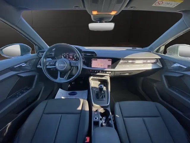 Vue intérieure avant de l'Audi A3 Sportback 2021 avec tableau de bord numérique, écran tactile et sellerie noire.