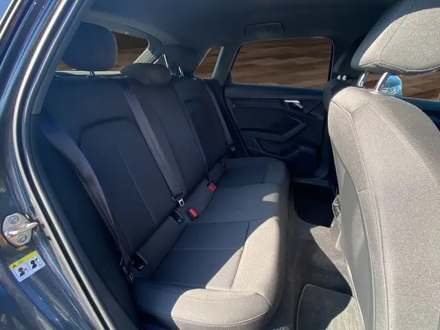 Vue intérieure arrière côté gauche de l'Audi A3 Sportback 2021 avec sièges tissu noir et vitres surteintées.