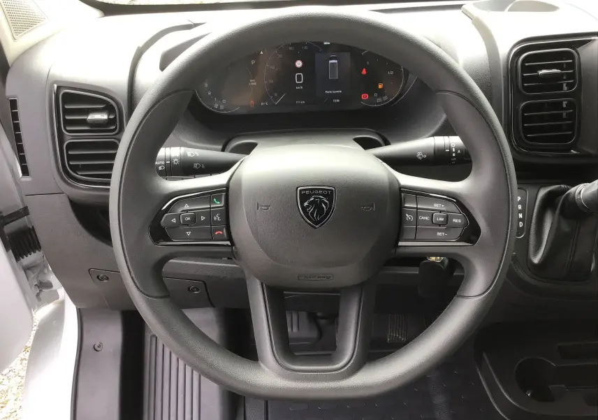 Vue rapprochée du volant noir du Peugeot Boxer Fourgon 2025 avec commandes intégrées et tableau de bord numérique.