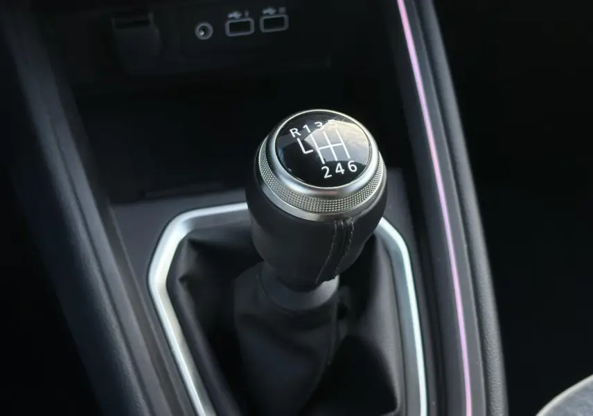 Gros plan sur le levier de vitesses manuel noir de la Renault Clio V TCe 90 Techno, entouré de garniture argentée.