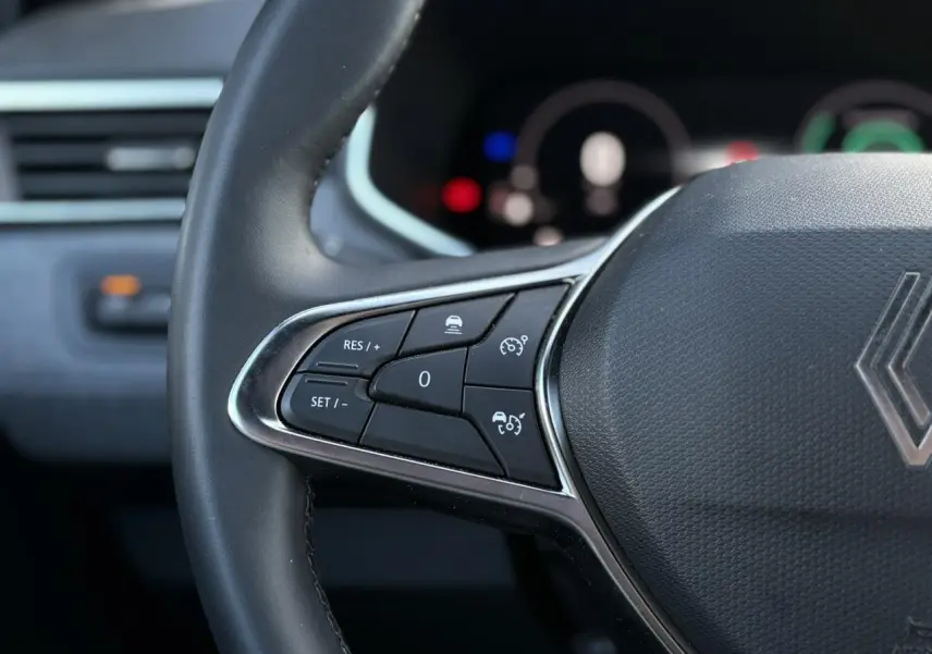 Gros plan sur le volant multifonction noir de la Renault Clio 2025 avec commandes de régulateur de vitesse.