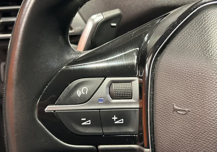 Gros plan sur les commandes de volume et téléphone au volant cuir noir du Peugeot 3008 Gris Artense 2022.