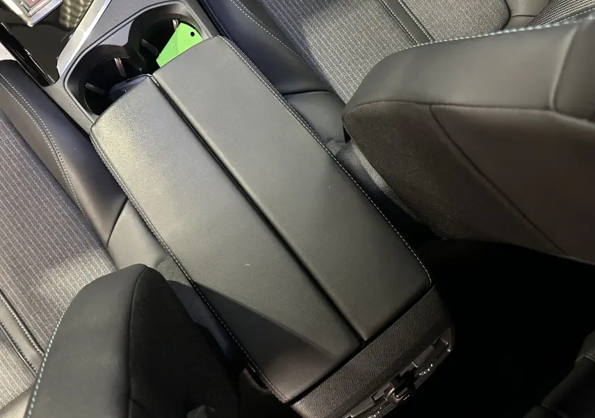 Vue plongeante sur l'accoudoir central noir et les sièges en tissu gris du Peugeot 3008 Puretech 130 EAT8 Allure 2022.