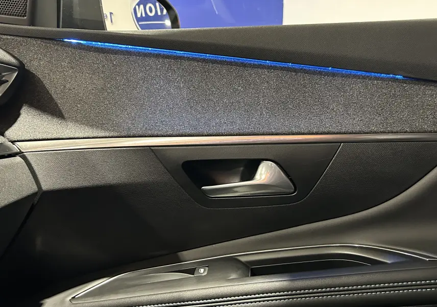 Détail de la porte côté gauche du Peugeot 3008 gris Artense, avec éclairage d'ambiance bleu et poignée argentée.