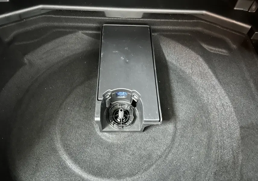 Vue rapprochée du coffre du Peugeot 3008 gris avec emplacement pour roue de secours et attelage visible.