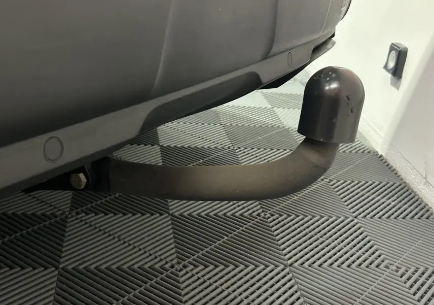 Gros plan sur l'attelage noir sous la partie arrière d'un Peugeot 3008 gris Artense avec toit noir.