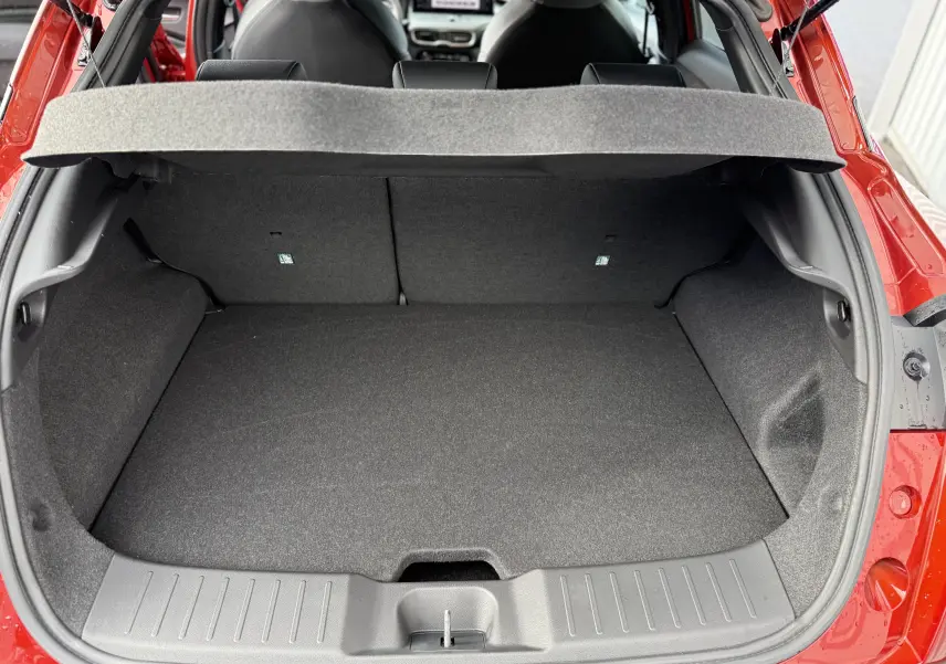 Coffre ouvert vu de l'arrière d'un Nissan Juke rouge Fuji 2025, montrant un espace de chargement propre et spacieux.