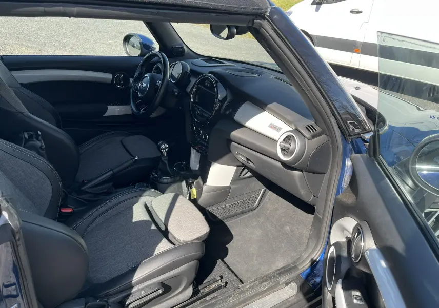 Vue intérieure côté conducteur d'une MINI Cabriolet F57 Cooper S bleu, avec sellerie tissu/cuir gris et volant multifonction.