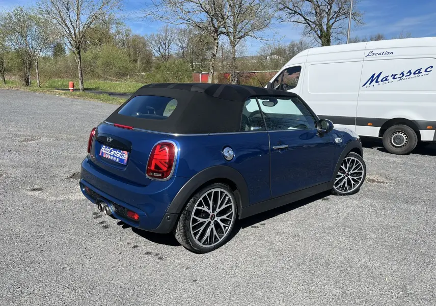 Vue 3/4 arrière droite d'une MINI Cabriolet bleu avec capote noire et jantes alliage bicolores, stationnée en extérieur.