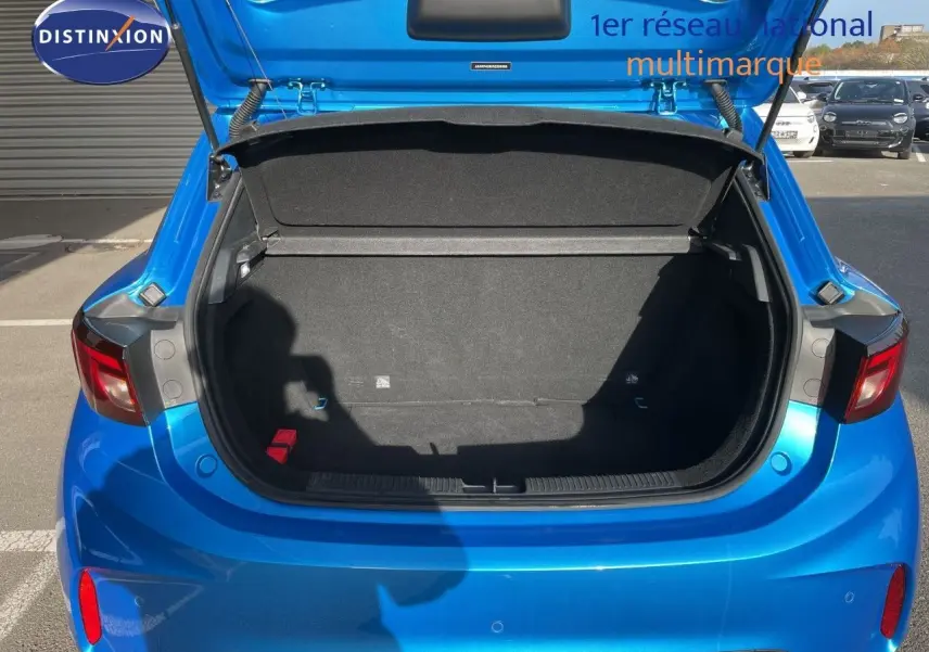 Coffre ouvert vu de l’arrière d’une MG3 1.5L HYBRID+ 195CH en bleu Como Metal, avec feux arrière visibles.
