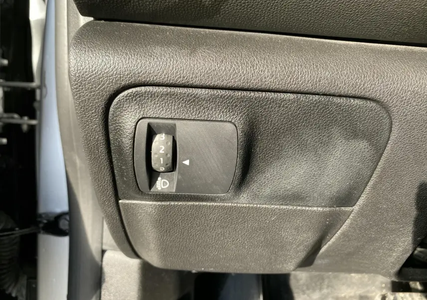 Gros plan sur le réglage d'intensité des phares côté conducteur d'une Renault Mégane IV Berline gris 2020.
