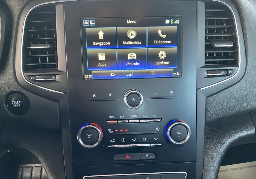 Vue rapprochée du tableau de bord noir de la Renault Mégane IV Berline avec écran tactile et commandes climatisation.