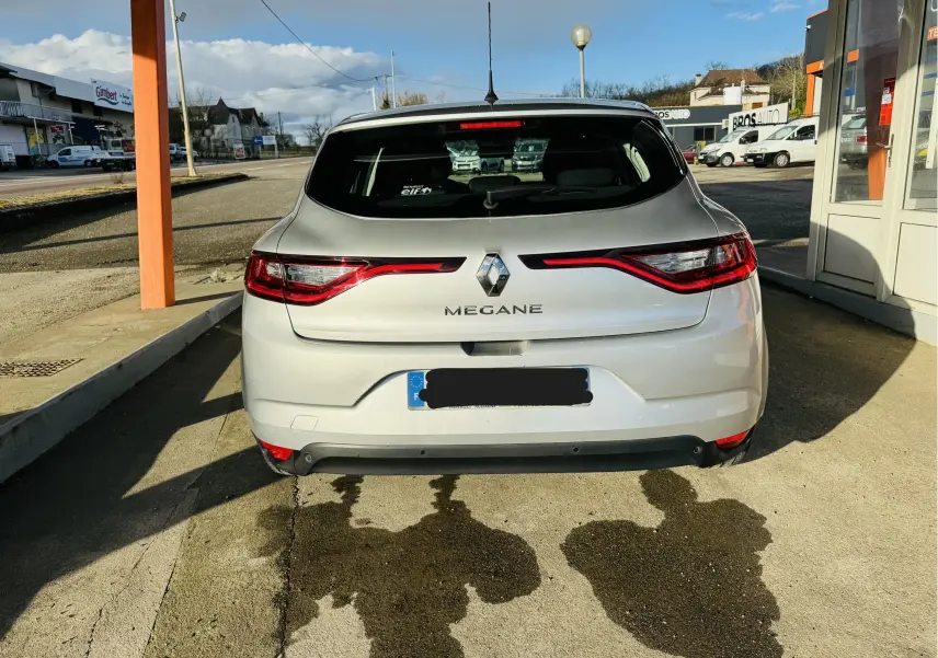 Vue arrière d'une Renault Mégane IV berline gris clair, avec feux arrière LED étirés et logo central visible.