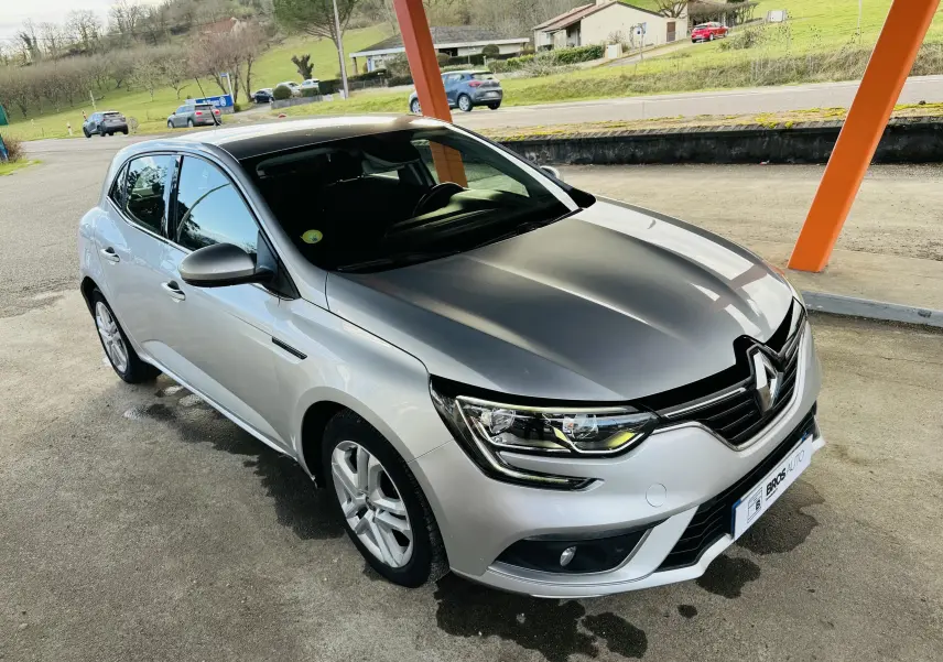 Renault Mégane IV berline gris clair avec capot noir, vue 3/4 avant droit sous abri orange.
