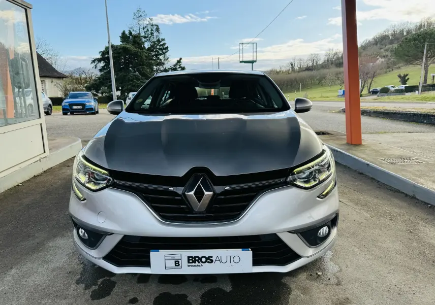 Vue frontale d'une Renault Mégane IV Berline gris métallisé avec phares LED et calandre noire brillante.