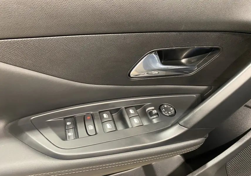 Gros plan sur la commande des vitres et la poignée intérieure côté gauche d'une Peugeot 308 noire Perla Nera 2024.