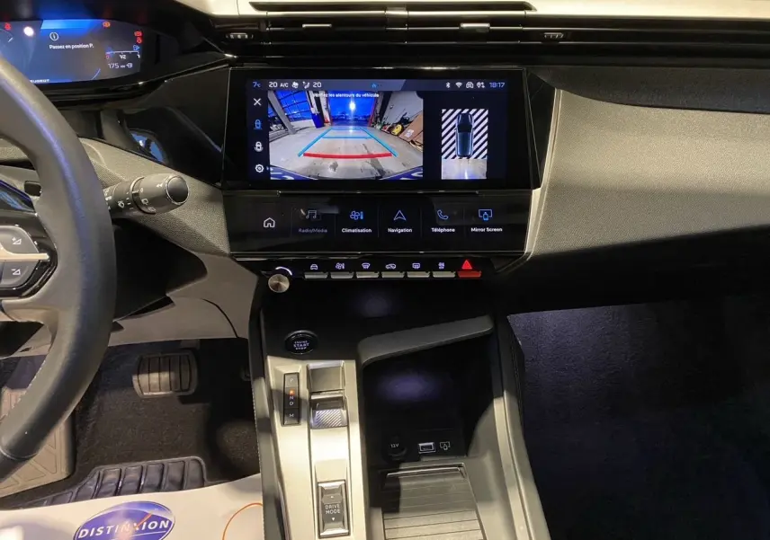 Vue intérieure du tableau de bord et console centrale de la Peugeot 308 noire, avec écran tactile affichant la caméra de recul.