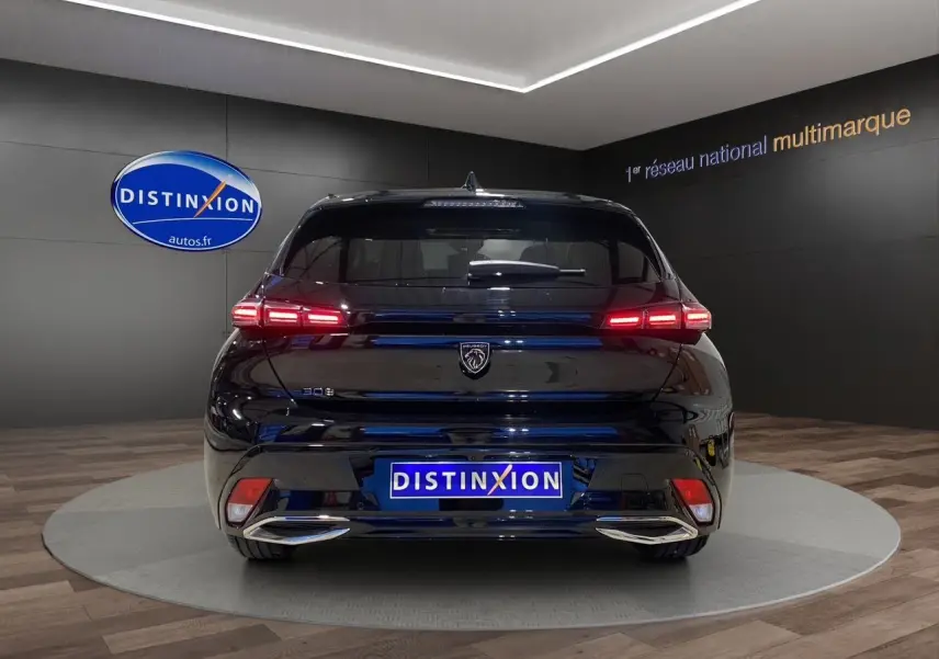 Vue arrière d'une Peugeot 308 noire Perla Nera avec feux LED allumés dans un showroom Distinxion.