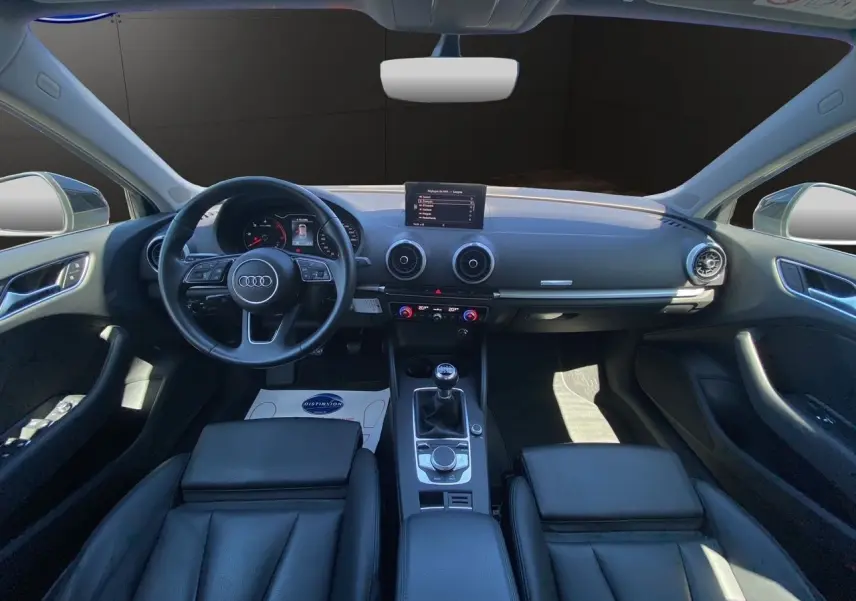 Intérieur noir d'une Audi A3 Sportback 2020, vue frontale du tableau de bord avec volant, écran et sellerie cuir chauffante.
