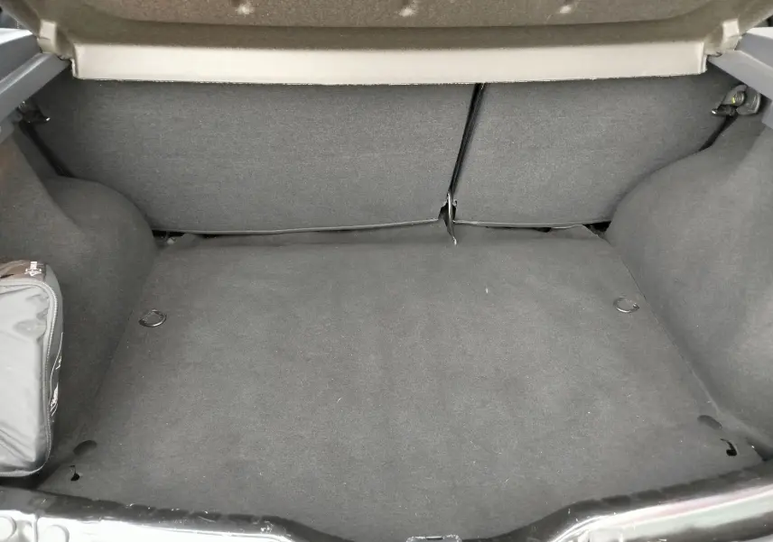 Coffre ouvert de Dacia Sandero noire 2011, vue intérieure montrant un espace de chargement propre et vide.