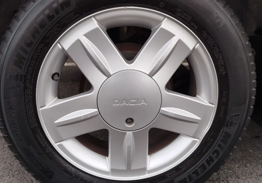 Gros plan sur la jante argentée de la Dacia Sandero noire, mettant en valeur le logo central et le pneu Michelin.