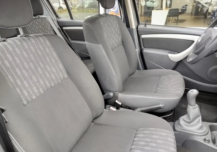 Intérieur de la Dacia Sandero noire 2011, vue côté droit sur les sièges avant en tissu gris avec volant cuir et levier de vitesse manuel.