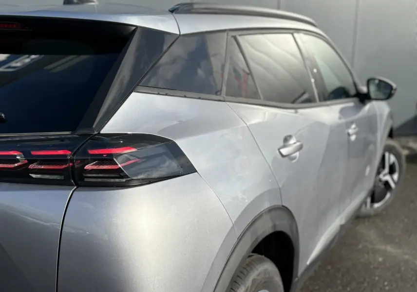 Vue 3/4 arrière droite d’un Peugeot 2008 Hybrid 145 gris Artense avec feux arrière LED à 3 griffes et jantes bi-ton.