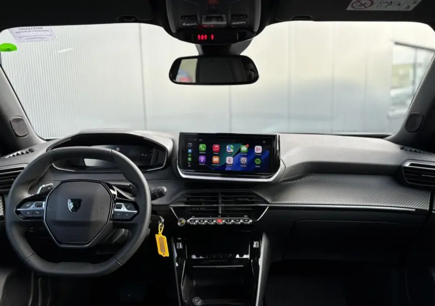 Vue frontale de l’habitacle noir du Peugeot 2008 Hybrid 145 Allure avec écran tactile central et volant compact cuir.