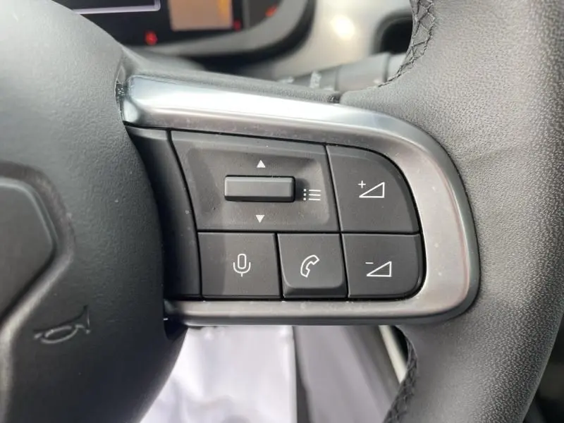 Gros plan sur les commandes multifonctions au volant du Jeep Avenger 2025, finition Summit, en cuir noir.