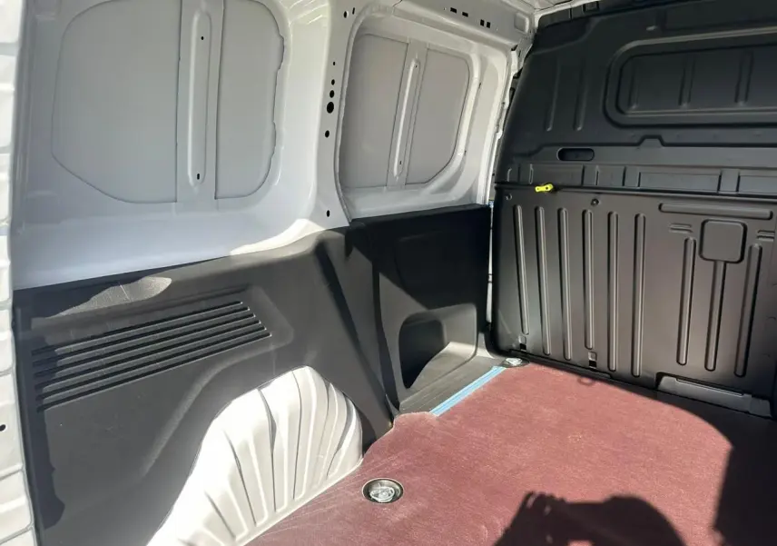 Vue intérieure de la zone de chargement arrière du Citroën Berlingo blanc Icy avec plancher bois antidérapant et parois noires.