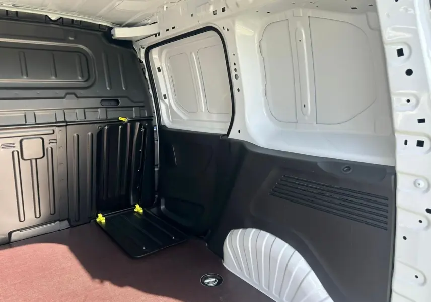 Vue intérieure côté droit du coffre blanc icy du Citroën Berlingo III Van avec plancher bois antidérapant et cloison fixe.