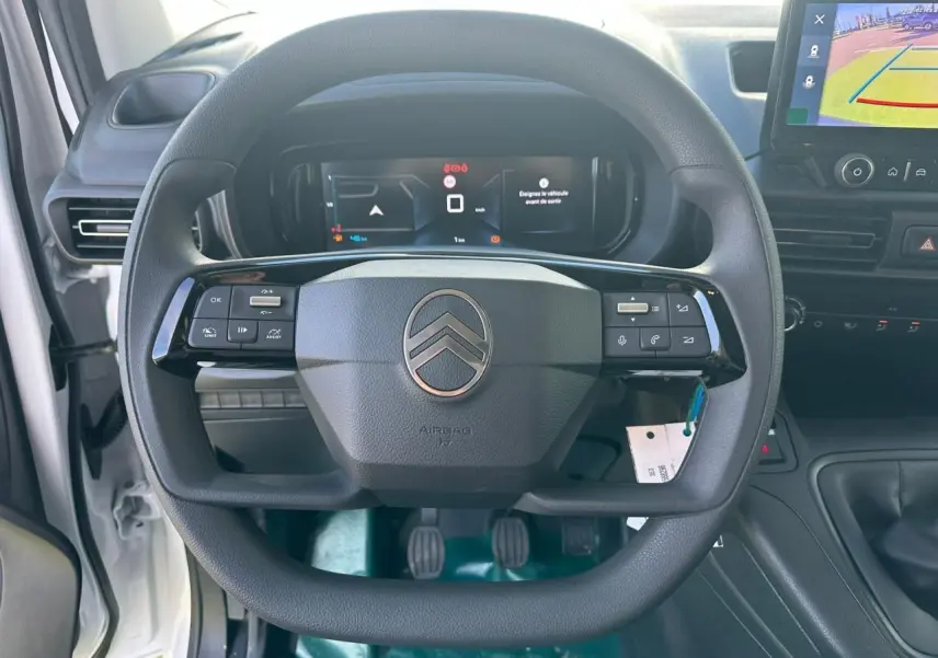 Vue intérieure centrée sur le volant multifonctions noir du Citroën Berlingo blanc avec tableau de bord numérique et écran tactile.