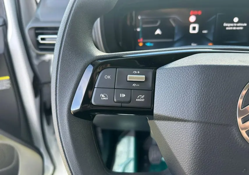 Gros plan sur le volant noir du Citroën Berlingo blanc Icy 2026, avec commandes multifonctions et tableau de bord numérique flou.