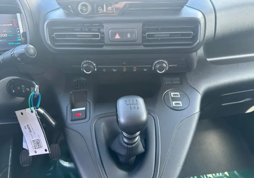 Vue rapprochée de la console centrale du Citroën Berlingo blanc, avec levier de vitesses manuel et commandes climatisation.